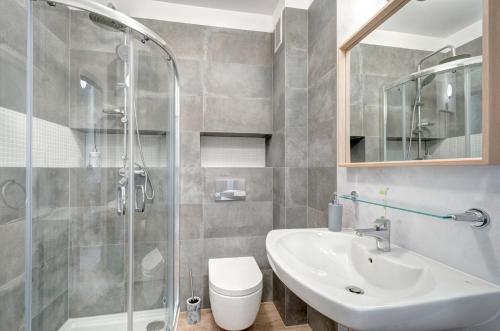 a bathroom with a sink and a toilet and a shower at Apartament Jantar Park in Jantar
