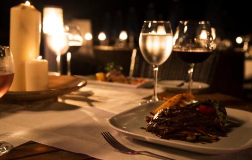 a plate of food on a table with glasses of wine at Torbahan Hotel in Torba