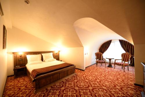 a bedroom with a bed and a table and chairs at Castel Transilvania in Baia Mare
