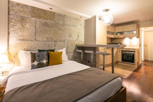 a bedroom with a large bed with a stone wall at Stay In Apartments in Porto