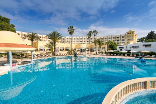 a large swimming pool with a hotel in the background at Steigenberger Marhaba Thalasso Hammamet in Hammamet