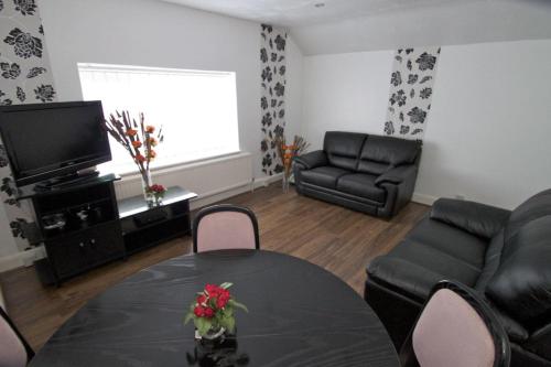 a living room with a table and a couch at La Suisse Serviced Apartments in Manchester