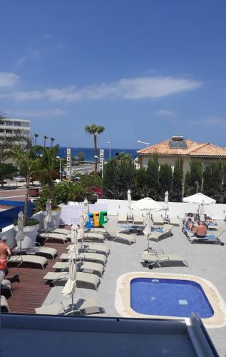 a group of lounge chairs and a pool at a resort at Protaras Plaza Hotel in Protaras