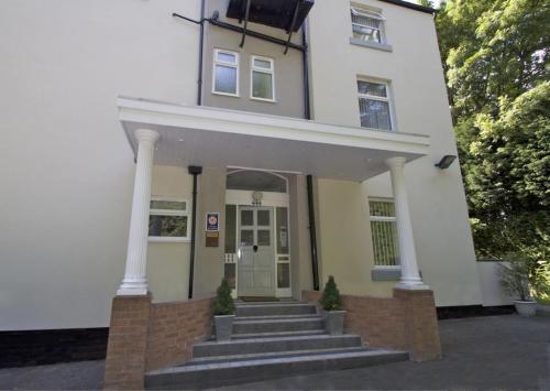 a white house with stairs in front of it at La Suisse Serviced Apartments in Manchester