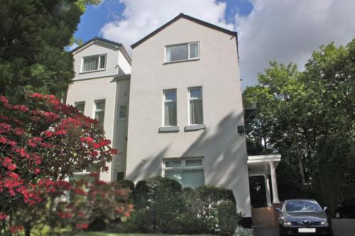a white house with a car parked in front of it at La Suisse Serviced Apartments in Manchester