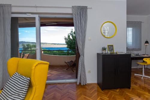 un salon avec une chaise jaune et un balcon dans l'établissement Captain's Apartment with Sea View, à Kraljevica