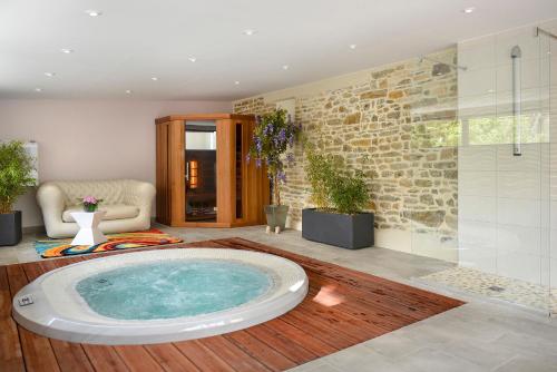 a large bathroom with a hot tub in a room at Logis Hotel Au Site Normand in Clécy
