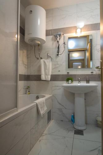 a white bathroom with a sink and a tub and a mirror at Apartment Barby - Deluxe in Banja Luka