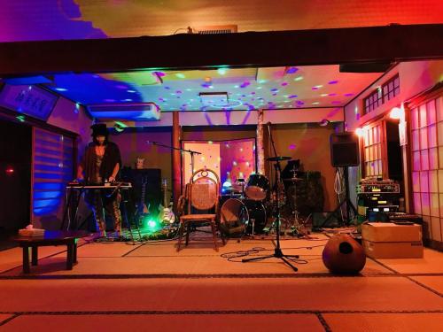 a man is on a stage with a band at わくわく自然体験の宿ゲストハウス山楽 in Itoigawa