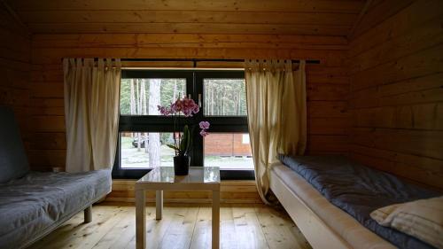 a room with two beds and a table and a window at Gryf-Balt Domki drewniane in Międzywodzie
