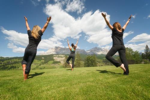 three women jumping in a field with their arms in the air at Hotel Lech Da Sompunt in Badia