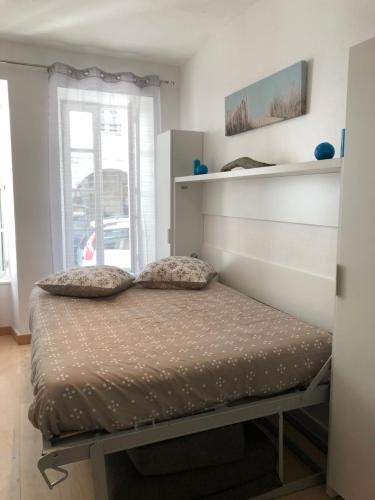 un lit avec deux oreillers dessus dans une chambre dans l'établissement Studio des Trois Ilets, à La Rochelle