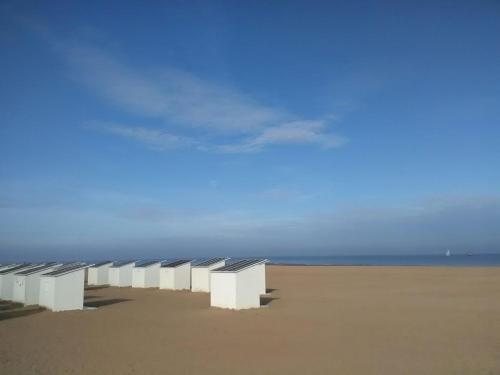 a row of white benches sitting on a beach at Seaview Loft in Ostend