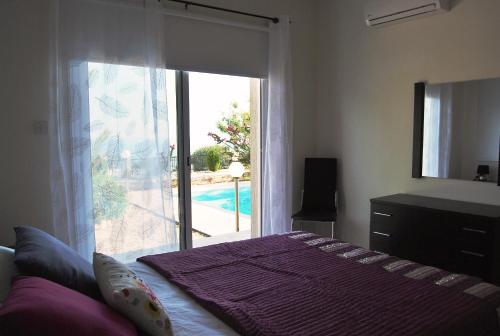 une chambre avec un lit et une porte coulissante en verre dans l'établissement Pegia Villa, à Peyia