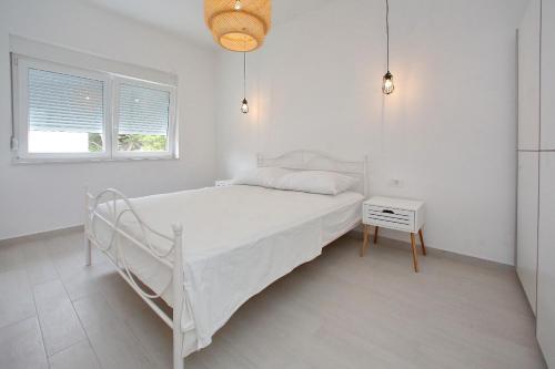 a white bedroom with a white bed and a table at Villa Maris in Bibinje