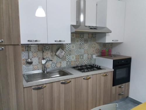 a kitchen with a sink and a stove top oven at Affacciati sulle Eolie Appartamenti sul Lungomare Patti Marina in Patti