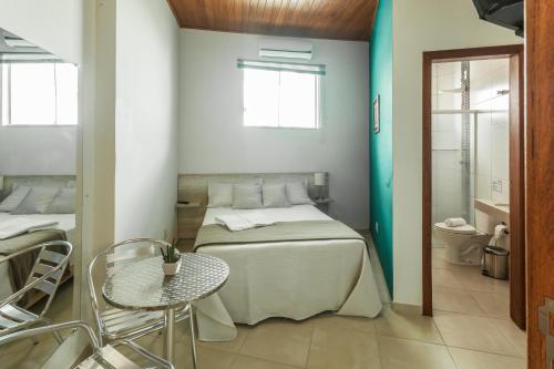 um quarto com uma cama, uma mesa e uma casa de banho em The Bridge Hostel Florianópolis em Florianópolis