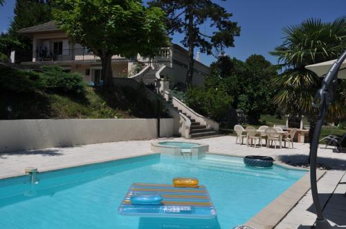 a swimming pool with chairs and a house at La Bourgeat in Chantesse
