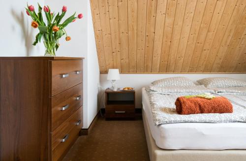 a bedroom with a bed and a dresser with a vase of flowers at Domki TORTUGA Debki in Dębki