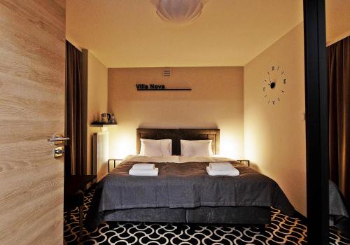 1 dormitorio con 1 cama con reloj en la pared en Villa Nova en Białystok