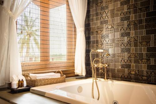 a bath tub in a bathroom with a window at Shinnabhura Historic Boutique Hotel in Phitsanulok