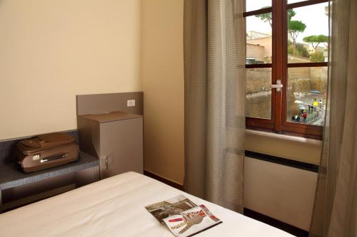 a room with a bed and a window and a suitcase at Hearth Hotel in Rome