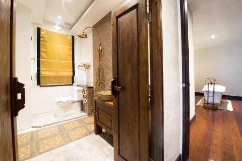 a bathroom with a toilet and a wooden door at Shinnabhura Historic Boutique Hotel in Phitsanulok
