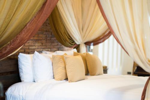 a bed with white pillows in a room with curtains at Shinnabhura Historic Boutique Hotel in Phitsanulok