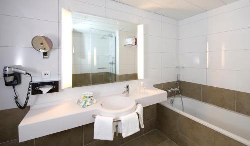 
a bathroom with a sink, toilet and mirror at Mercure Carcassonne Porte De La Cité in Carcassonne
