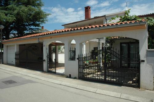 une maison blanche avec une arche et une clôture dans l'établissement Apartments Valbandon, à Fažana
