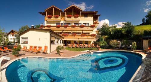 a hotel with a large swimming pool in front of a building at Wanderhotel Teiserhof in Funes