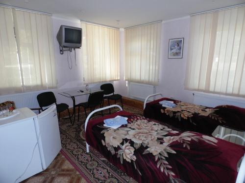 a room with two beds and a table and a tv at Na Admirala Makarova in Mykolaiv