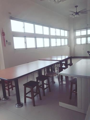 a group of tables and chairs in a room with windows at Jinlun Village Homestay in Taimali