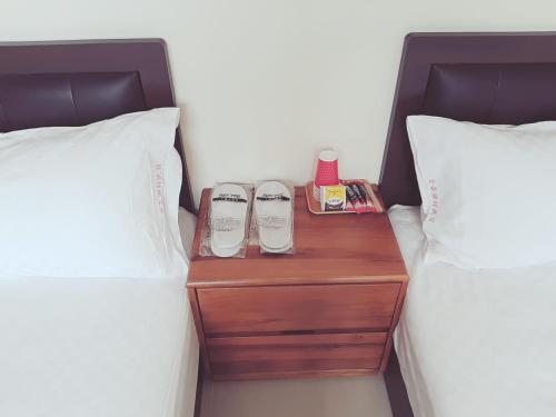 a nightstand between two beds with shoes on it at Jinlun Village Homestay in Taimali