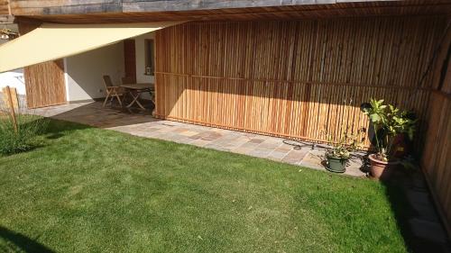 a backyard with a patio with a table and grass at Guest House Dolomiti in Baselga di Pinè