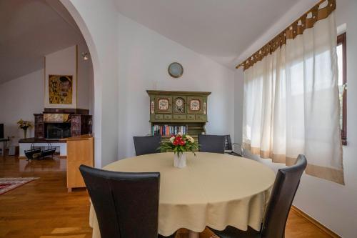 a dining room table with chairs and a vase of flowers on it at Apartments Dedić in Supetarska Draga