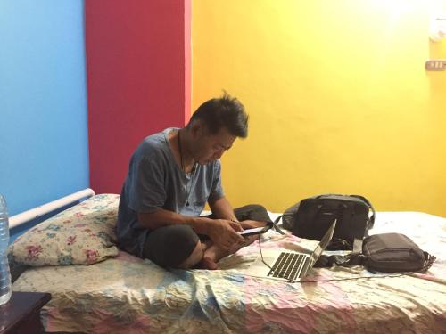 a man sitting on a bed with a laptop computer at david hostel in Aswan