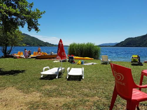 a group of chairs and umbrellas on the grass near a lake at Casa dei Mulini in Mergozzo