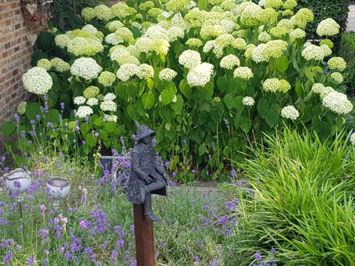 a statue of a cat sitting on a post in a garden at The Two Oaks - Private garden for guests in Hertsberge