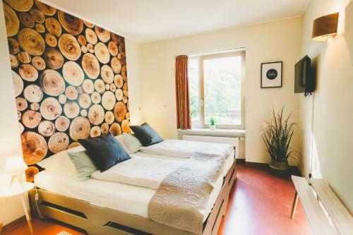een slaapkamer met 2 bedden en een grote muur van houtblokken bij Ostel Jugendhotel Bremervörde in Bremervörde