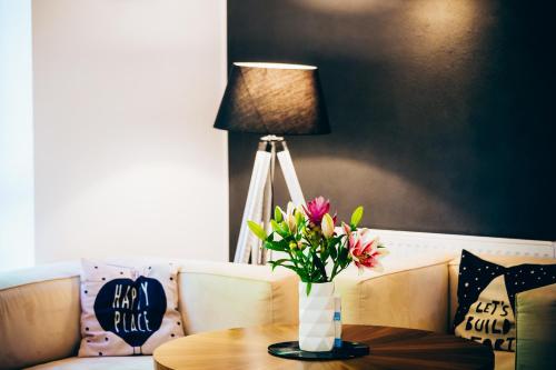 a vase of flowers on a table with a lamp at Ostel Jugendhotel Bremervörde in Bremervörde