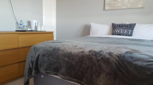 a bedroom with a bed and a wooden dresser at Haus Serviced Living in Braintree