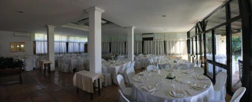 un salón de banquetes con mesas blancas y sillas blancas en Hotel Della Baia, en Baia Domizia