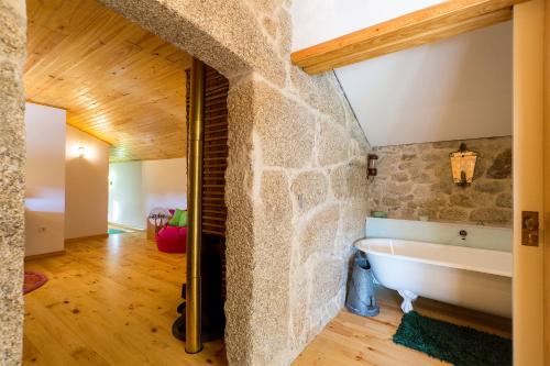 y baño con pared de piedra y bañera. en Casa Sardão, en Trofa
