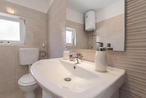 a white bathroom with a sink and a toilet at Apartments HIPERION in Zadar