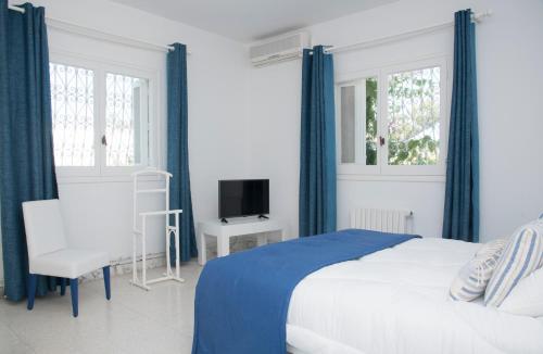 Un dormitorio blanco con una cama y un televisor. en Villa"Dar Janna", en Hammamet