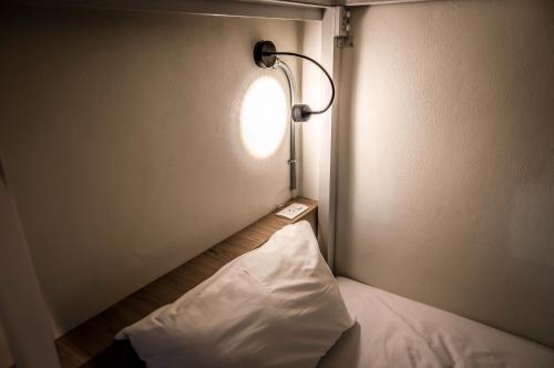a small room with a bed with a light on it at Jam Hostel Bangkok in Bangkok