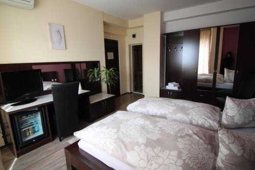 a bedroom with a bed and a desk and a television at Hotel Poarta Transilvaniei in Bistriţa