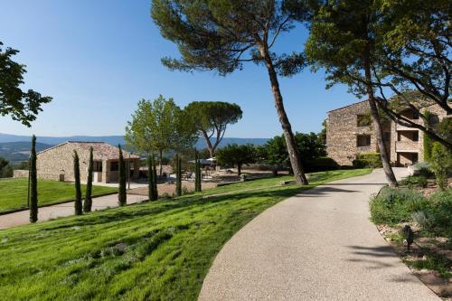 a path through a park with trees and a building at Mas des Herbes Blanches Hôtel & Spa – Relais & Châteaux in Joucas