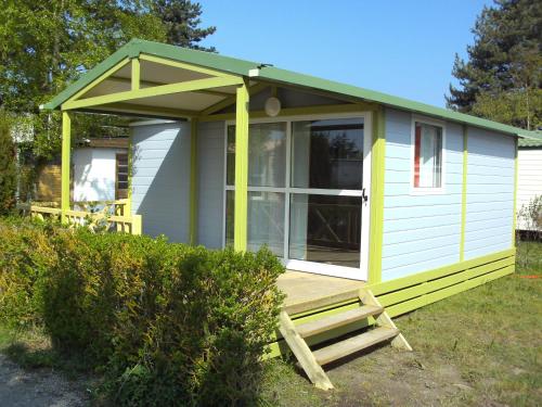 une petite maison verte et blanche avec une terrasse couverte dans l'établissement Camping Pomme de Pin, à Stella-Plage